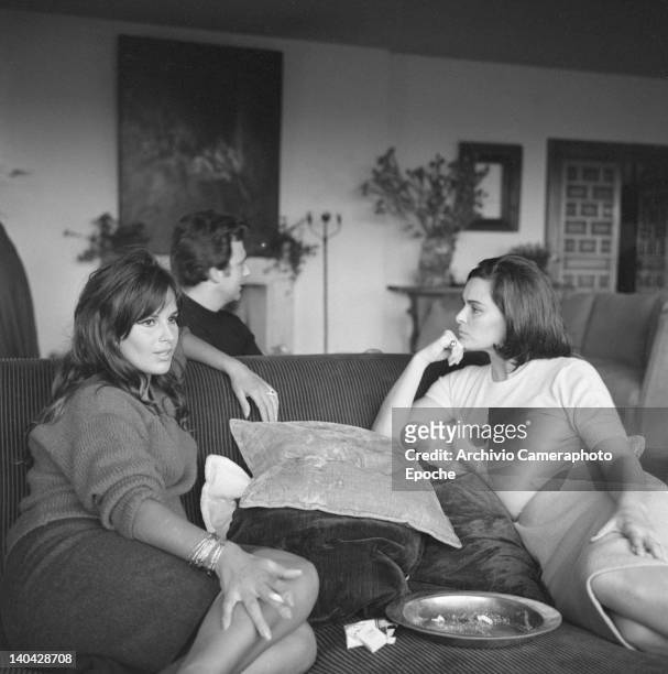 Italian actress Lucia Bose with Franco Interlenghi and Antonella Lualdi sitting on a sofa and smoking a cigarette, Madrid, 1961.