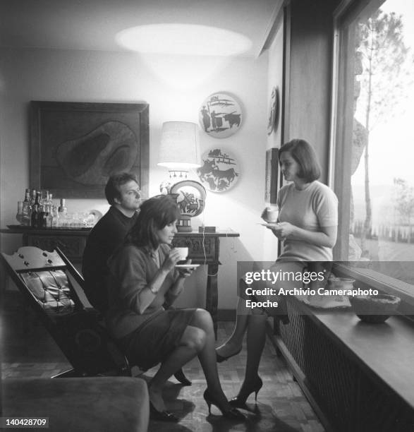 Italian actress Lucia Bose with Franco Interlenghi and Antonella Lualdi sitting beside the window sipping a cup of tea, Madrid, 1961.