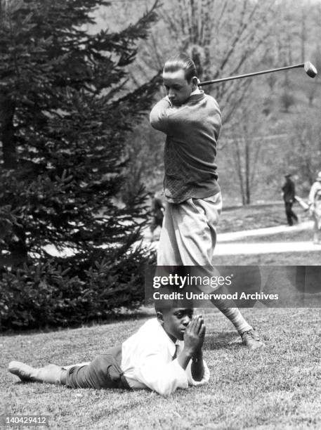 Fred Glimes, golf instructor at Hot Springs, tees off the head of his praying caddy, Hot Springs, Virginia, May 8, 1926.