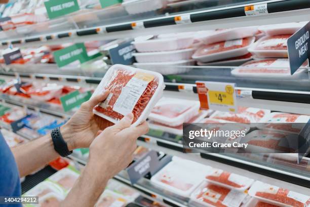 man checks price of ground beef at supermarket - carne foto e immagini stock