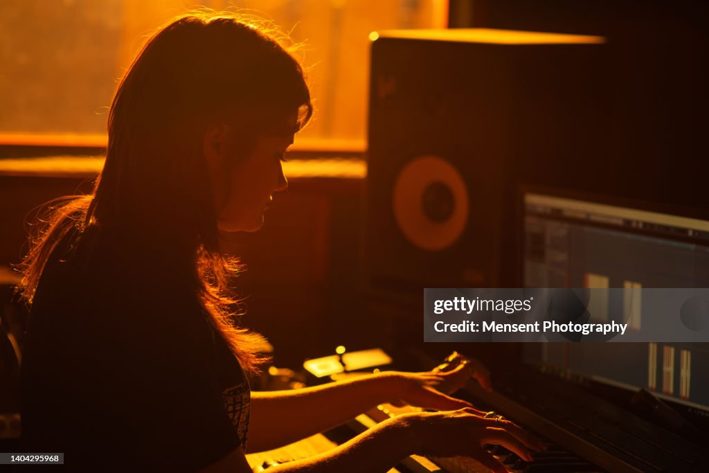 Woman music producer working on audio equipment control panel in professional music recording studio at sunset light