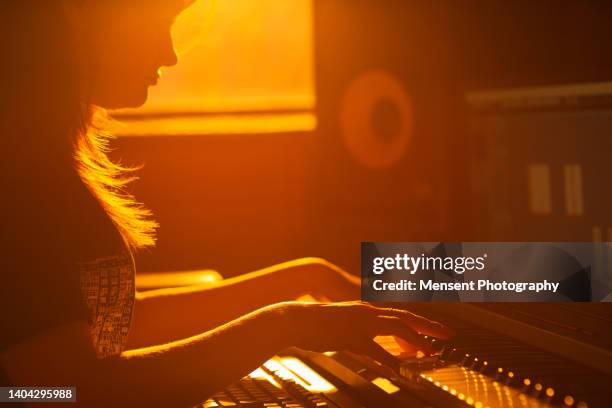 woman music producer playing piano in evening in recording music studio - music producer stock pictures, royalty-free photos & images