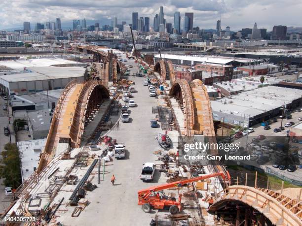 Under a dramatically cloudy sky a close aerial view towards downtown of the activity on the bridge deck between the wooden falsework arches during...