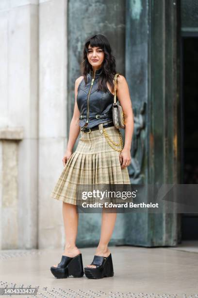 Maria Bernad wears a black shiny leather zipper / sleeveless / belted gilet, a beige and brown GG monogram print pattern shoulder bag from Gucci,...