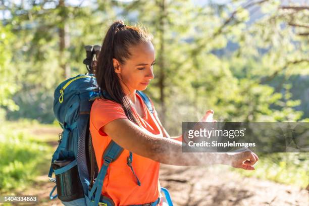a woman applies mosquito spray to her hands during hiking. - insect bites images - fotografias e filmes do acervo