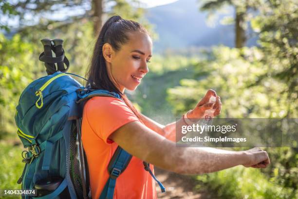 a woman applies mosquito spray to her hands during hiking. - tick bite stock pictures, royalty-free photos & images