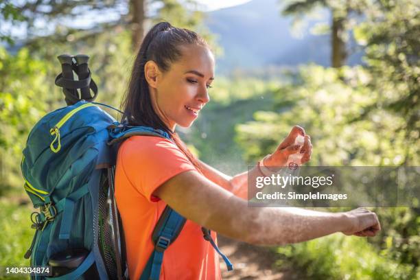 a woman applies mosquito spray to her hands during hiking. - fly spray stock pictures, royalty-free photos & images