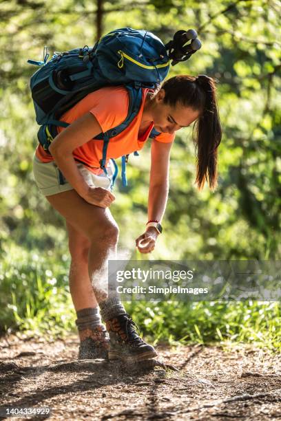 a woman applies mosquito spray to her feet during hiking. - insect spray stock pictures, royalty-free photos & images