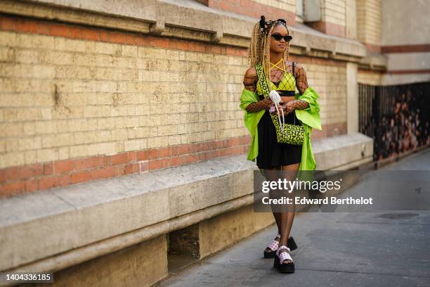 Debbie aka @blackhey wears a black velvet hair elastic, black sunglasses, a silver embossed patter earrings from Givenchi, a large fishnet / mesh...