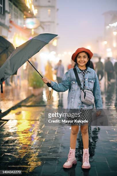 portrait of a cute girl holding umbrella standing on the city street - enjoy monsoon stock-fotos und bilder