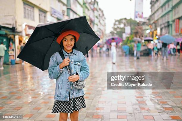 portrait of  a cute girl holding an umbrella standing on the city street - enjoy monsoon stock-fotos und bilder