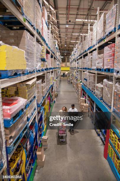 couple shopping in large wholesale store, man reading shopping list from mobile phone - full size stock-fotos und bilder