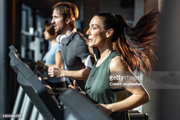 athletic woman running on treadmill in a gym. - health club stock pictures, royalty-free photos & images