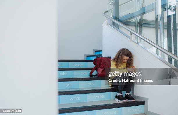 sad little girl sitting in school stairs. - bullying stock pictures, royalty-free photos & images
