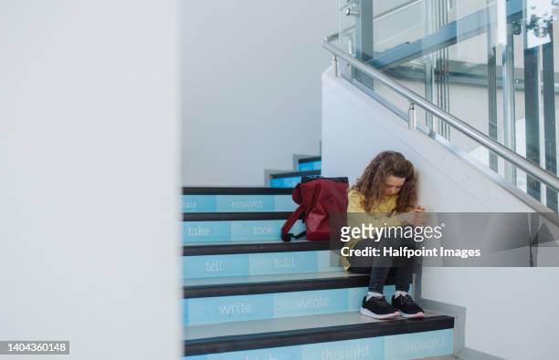 sad little girl sitting in school stairs. - bullying escolar - fotografias e filmes do acervo