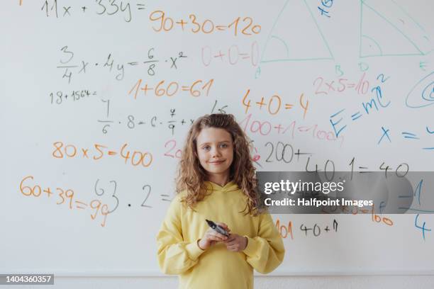 little girl standing in front of school board, mathematic class. - mathematik stock-fotos und bilder