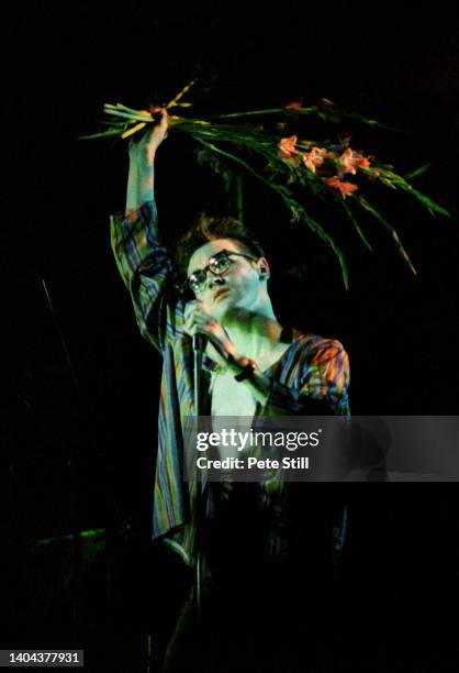 Morrissey of The Smiths holds a bunch of gladioli aloft while performing on stage at Hammersmith Palais, on March 12th, 1984 in London, England.