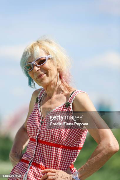 fashionable senior woman with colored blue hair smiling and looking at camera - frau haarsträhne blond beauty stock-fotos und bilder