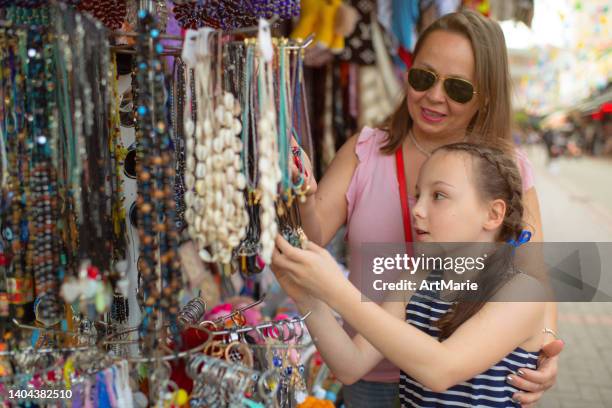 little girl with mother choosing souvenirs while traveling in turkey - craft show stock pictures, royalty-free photos & images