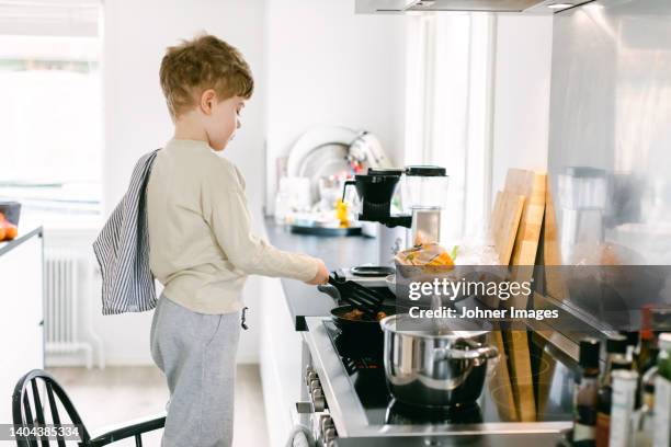 boy preparing food in kitchen - keramische plaat stockfoto's en -beelden