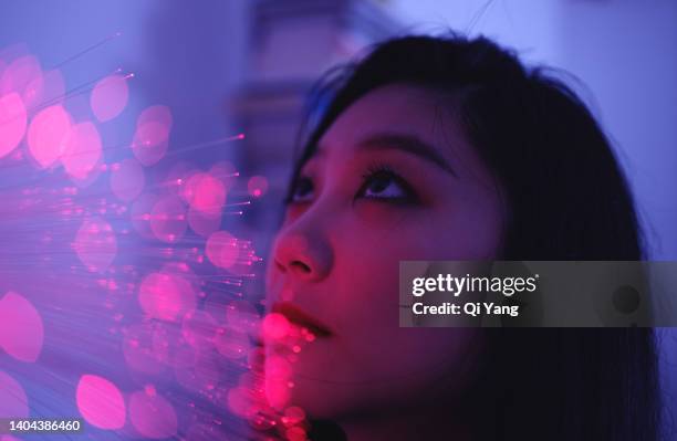 technology concept. young asian woman standing on glowing fiber optic background - perception sensorielle photos et images de collection