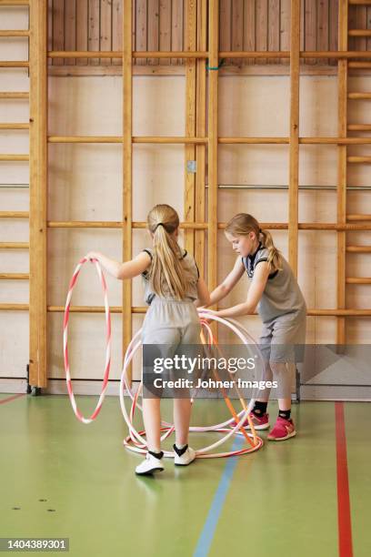children playing with hula hoops in school gym - school gymnastics stock pictures, royalty-free photos & images