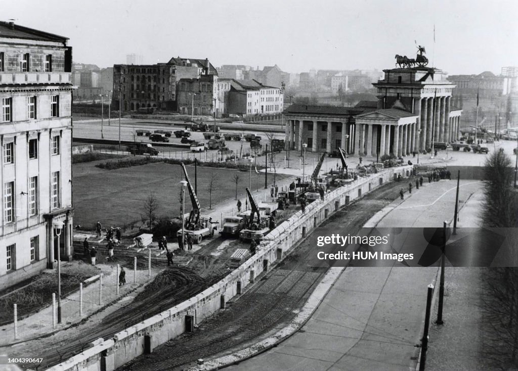 Berlin wall reinforced. Under the watchful eye of Communist police, East german workers near the Brandenburg Gate reinforce the wall dividing the city. Since erecting the wall on August 13, 1961, to stop the flow of East Germans into West Berlin, the East