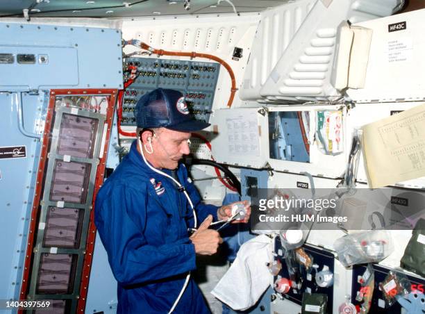 --- Astronaut Thomas K. Mattingly II, STS-4 crew commander, prepares a meal in the middeck area of space shuttle Columbia. He uses scissors to open a...