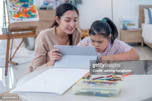 teacher teaching an autistic girl student to use an e-learning program from a tablet. - special education stock pictures, royalty-free photos & images