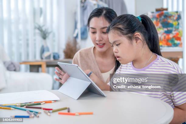 teacher teaching an autistic girl student to use an e-learning program from a tablet. - special education stock pictures, royalty-free photos & images