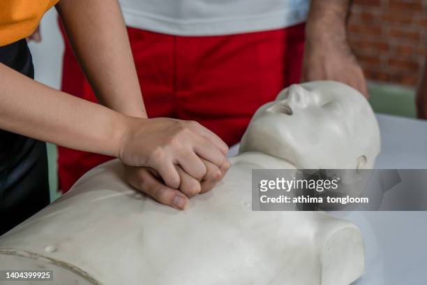 first-aider practising chest compressions on a cpr training dummy. - aider stock pictures, royalty-free photos & images