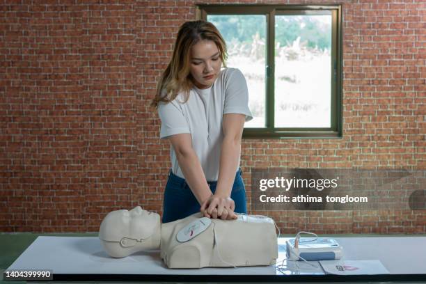 first-aider practising chest compressions on a cpr training dummy. - aider stock pictures, royalty-free photos & images