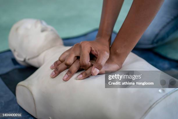 closeup hands practicing chest compressions on a cpr training dummy. - wiederbelebung stock-fotos und bilder