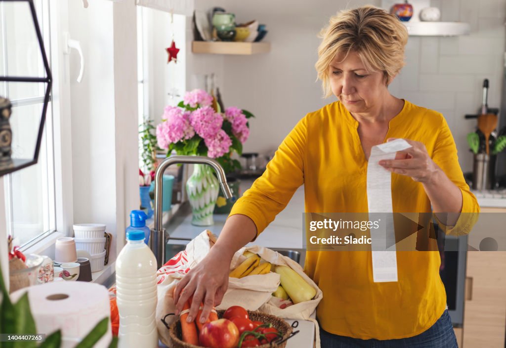 Mature woman going through her receipts at home after buying groceries