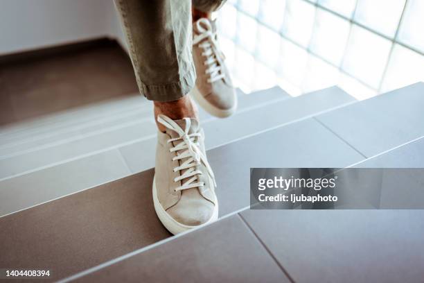 closeup shot of an unrecognizable businessman walking up a staircase in an office - stairs stock pictures, royalty-free photos & images