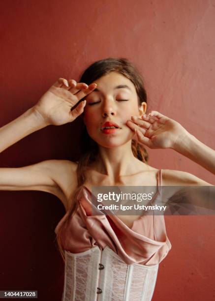 brunette woman covering face with hands - vintage corset stock-fotos und bilder