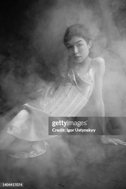 brunette woman sitting in corset and dress - vintage corset stockfoto's en -beelden