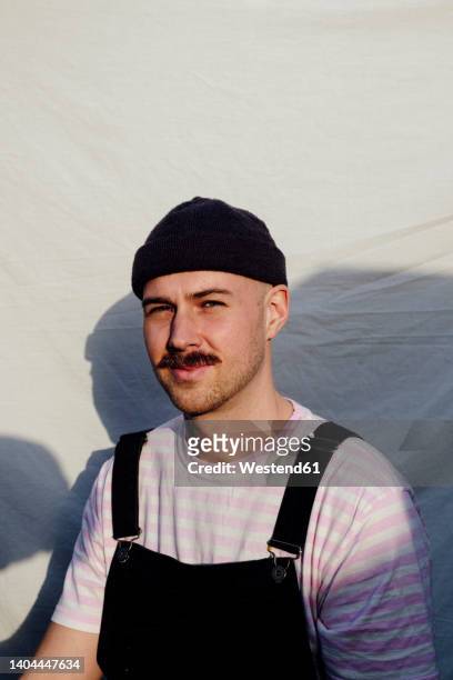 smiling man wearing knit hat in front of white backdrop - bib overalls 個照片及圖片檔