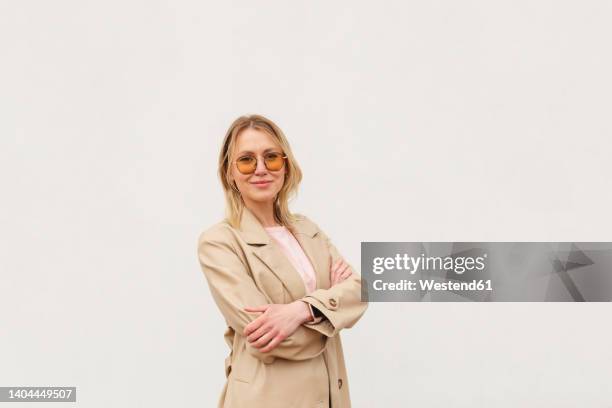 confident woman with arms crossed standing against white background - frau mittleren alters stock-fotos und bilder