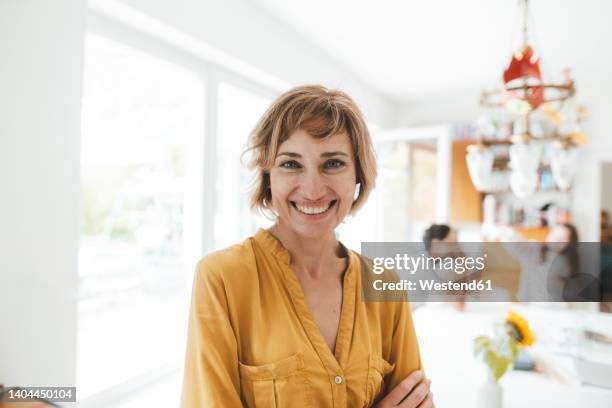 happy woman with blond hair standing at home - men women & children film stock-fotos und bilder