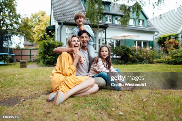 happy family sitting in front of house at back yard - family back yard stockfoto's en -beelden