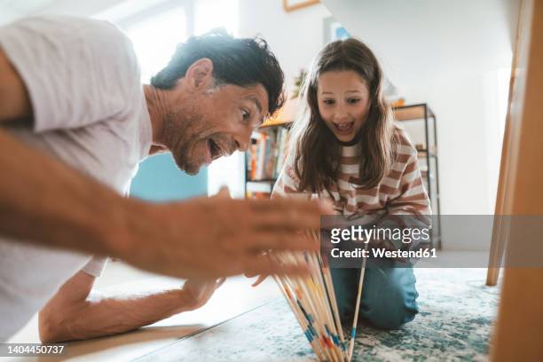 surprised father and daughter playing mikado at home - mikado stock pictures, royalty-free photos & images