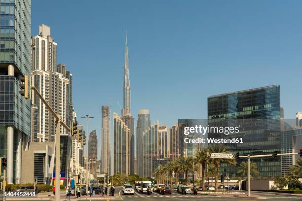 united arab emirates, dubai, busy street in business bay district with tall skyscrapers in background - burj khalifa stock-fotos und bilder