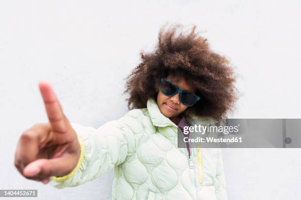 girl with sunglasses showing index finger in front of wall - index finger fotografías e imágenes de stock