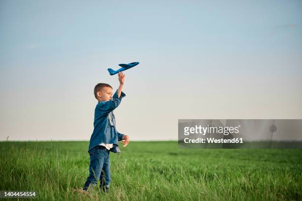 boy throwing airplane toy in field on weekend - model airplane ストックフォトと画像