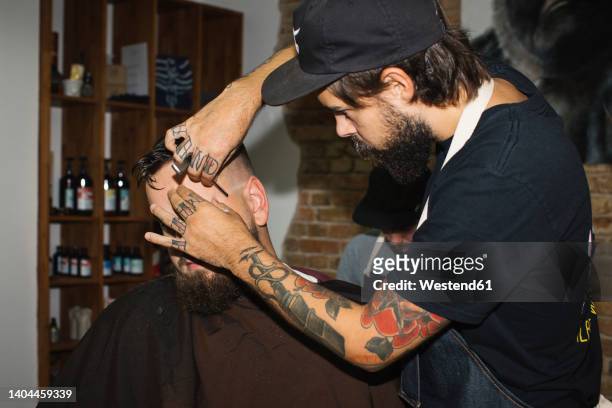 man in barber shop getting his beard shaved with razor blade - razor blade stockfoto's en -beelden