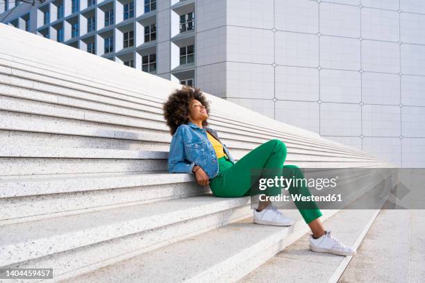 smiling woman with eyes closed sitting on steps - denim jacket stock pictures, royalty-free photos & images