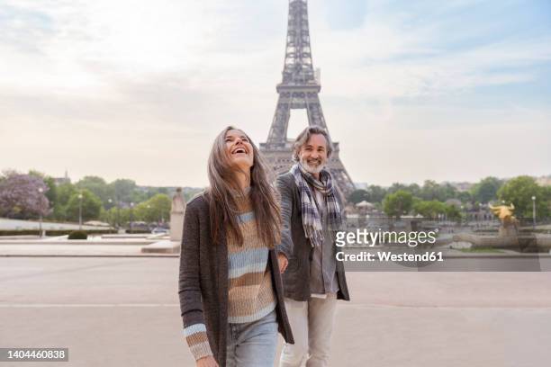 happy mature couple in front of eiffel tower, paris, france - couple paris stock-fotos und bilder