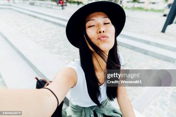 beautiful young woman wearing hat puckering lips - puckering stock pictures, royalty-free photos & images