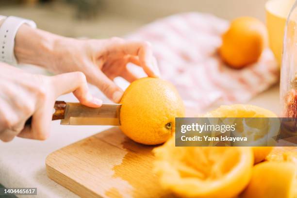 close-up of a woman slicing oranges for cold refreshing drink - orange stock-fotos und bilder